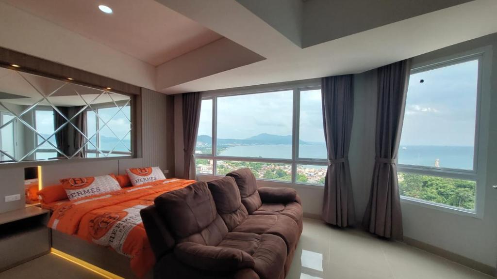 ein Schlafzimmer mit einem Bett, einem Sofa und Fenstern in der Unterkunft APARTEMEN THE BAY LAMPUNG CITY MALL in Bandar Lampung