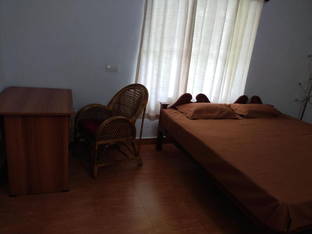 a bedroom with a bed and a desk and a window at Mary's homestay in Kalpetta