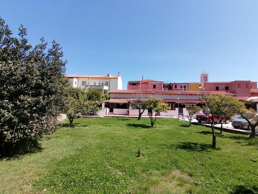 a green yard with trees in front of buildings at Appartamento centralissimo in San Teodoro in San Teodoro