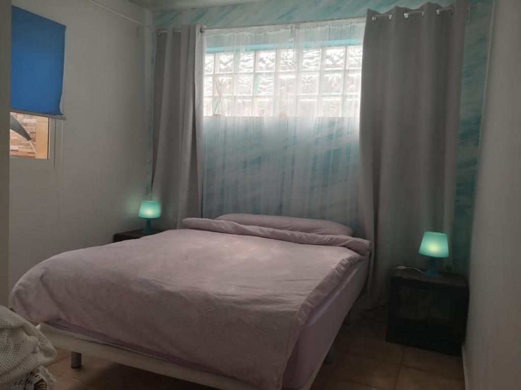 um quarto com uma cama com uma janela e 2 candeeiros em finca Lotusflower em Aguatona