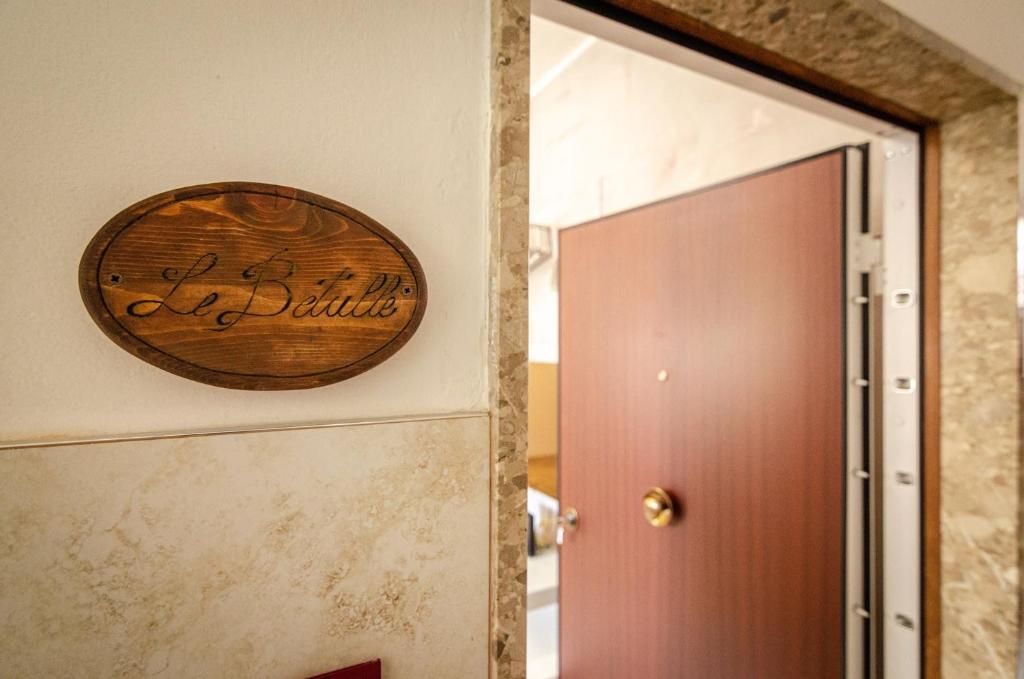een houten bord op een muur naast een deur bij B&B Corsini in Bologna
