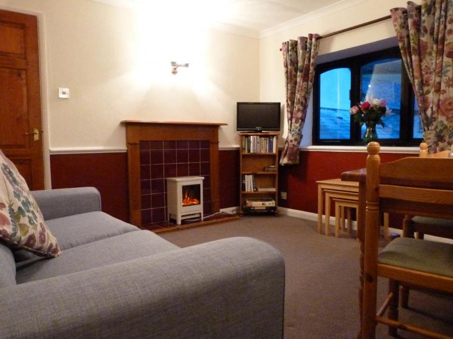 a living room with a couch and a fireplace at Primrose Cottage, Triscombe Farm Cottages in Wheddon Cross