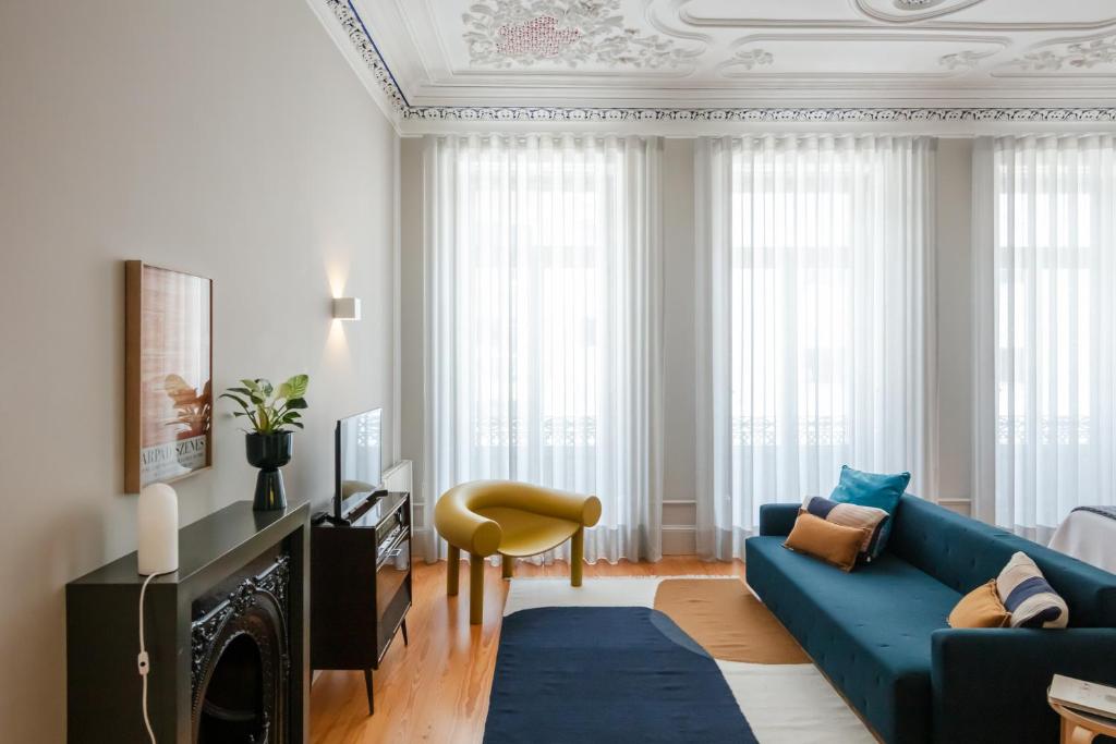 a living room with a blue couch and a chair at Baumhaus Serviced Living - Art & Design Apartments in Porto
