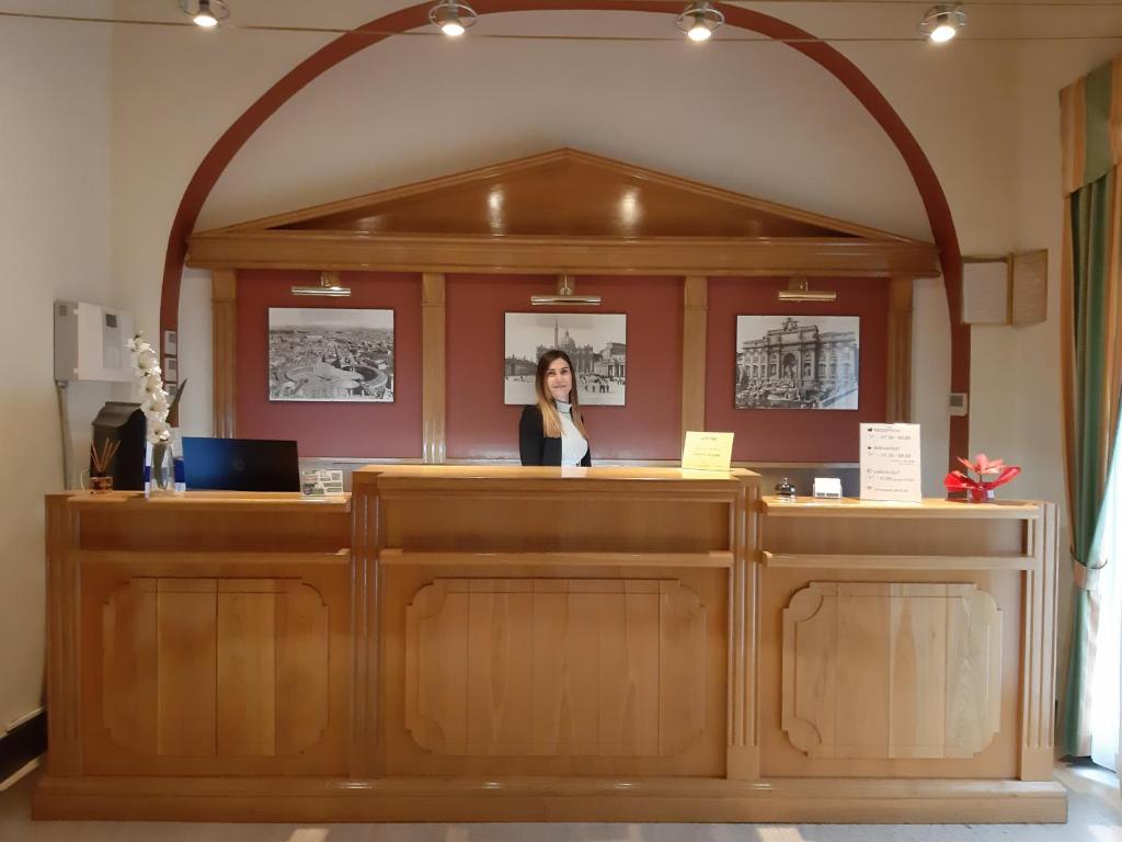 Una donna sta dietro un bancone in un ufficio di Hotel Mariano a Roma