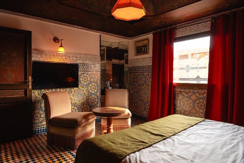 a bedroom with a bed and a chair and a window at LUXURY apartment in Marrakesh