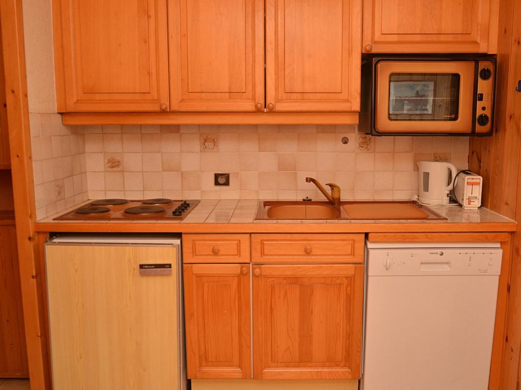 Kuchnia z drewnianymi szafkami, zlewem i kuchenką mikrofalową w obiekcie Studio lumineux au centre de Flaine avec balcon et kitchenette - FR-1-425-152 w mieście Flaine