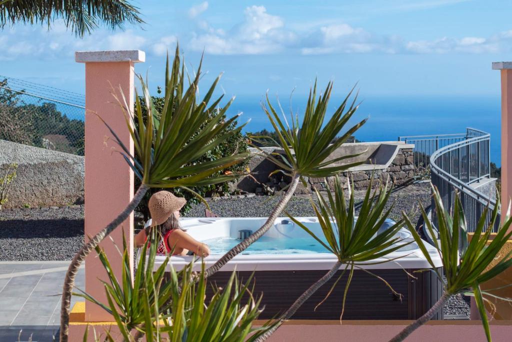 una bañera de hidromasaje al lado de una casa con plantas en With jacuzzi sea view - Casa da Quinta Grande, en Câmara de Lobos