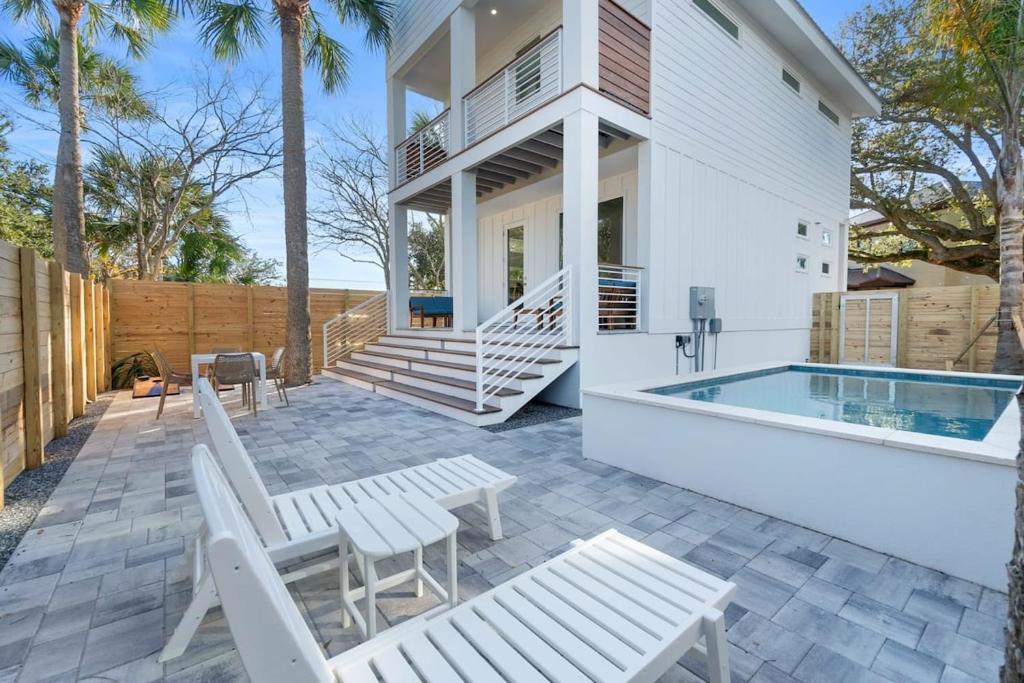 a patio with white chairs and a swimming pool at Sunset Cove - Heated Pool - Sea Views - Walkable in Saint Augustine