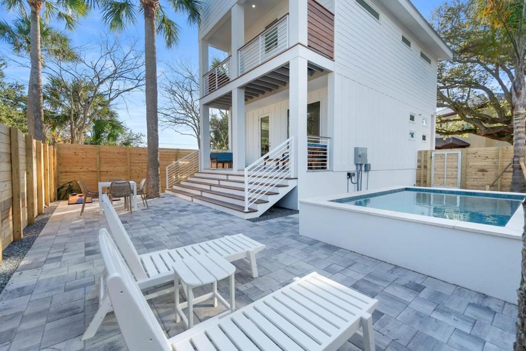 eine Terrasse mit weißen Stühlen und einem Pool in der Unterkunft Sunset Cove - Heated Pool - Sea Views - Walkable in St. Augustine