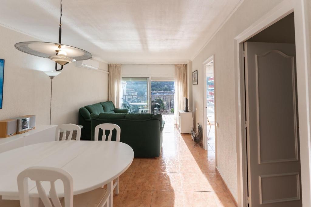 a living room with a white table and a green couch at Apartamento Pau Picasso con terraza Tossa de Mar in Tossa de Mar