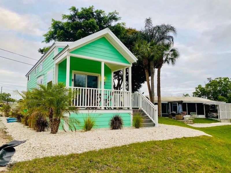 a green house with a porch on a beach at Pinecraft Tiny Home 'Green Parrot ' in Sarasota