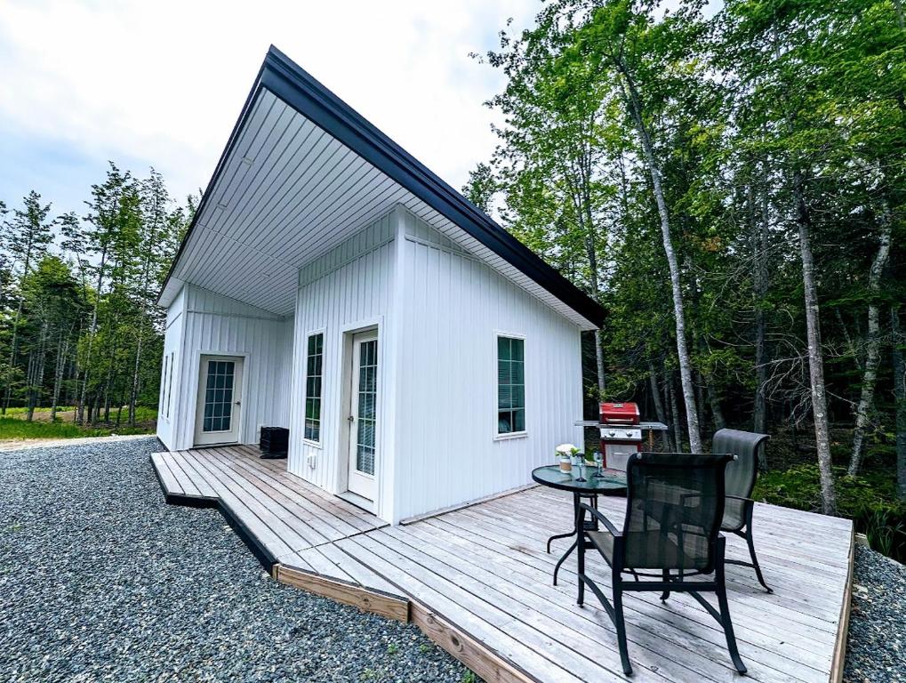 a small white shed with a table on a wooden deck at Captains Quarters by the Beach in Ellsworth