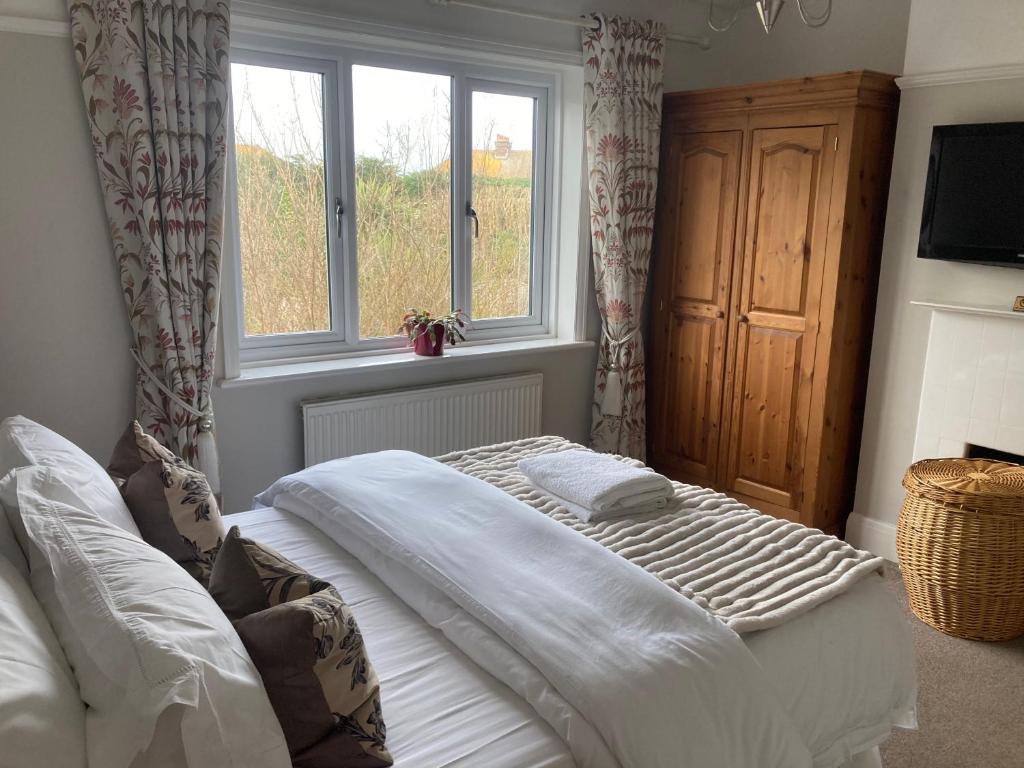 a bedroom with a bed and two windows at ABI B&B in Kent