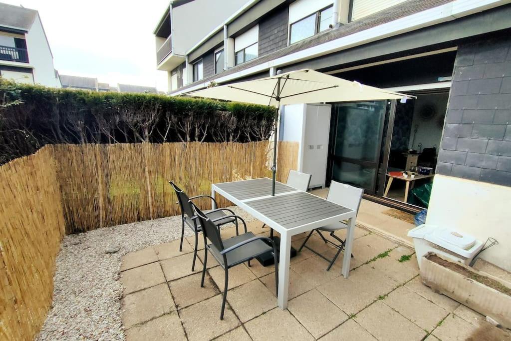 een tafel en stoelen met een parasol op een patio bij Appt RdC terrasse, 300m plage. in Courseulles-sur-Mer