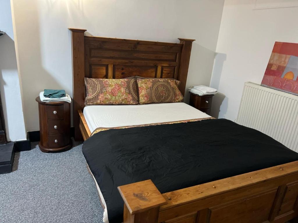 a bedroom with a large bed with a wooden headboard at Antic Cottage for Family in Nottingham