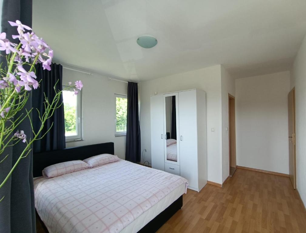 um quarto com uma cama e um vaso com flores roxas em Villa Meadow em Kobiljača