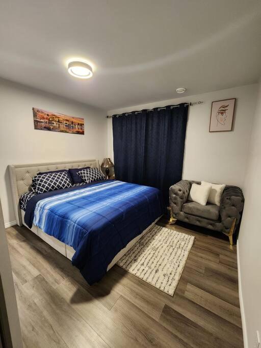 a bedroom with a blue bed and a chair at Cozy one bedroom in Airdrie in Airdrie