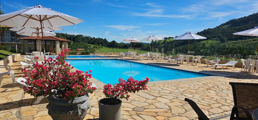 una piscina con flores y sombrillas en Filimahalo Hotel, en Serra Negra