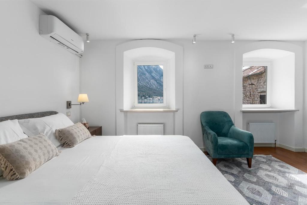 una camera bianca con un letto e una sedia verde di Casa Spada by Belsize a Kotor (Cattaro)