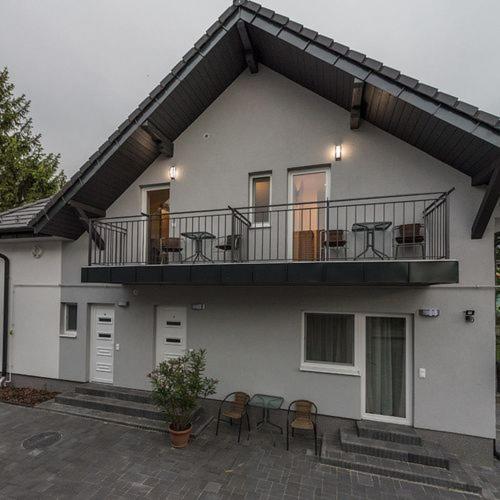 a house with a balcony with tables and chairs at Kikötő Anna Apartmanok in Balatonboglár