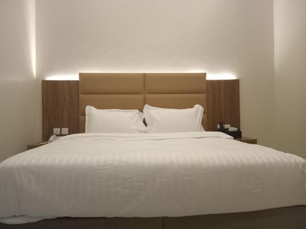 sypialnia z dużym łóżkiem z białą pościelą i poduszkami w obiekcie فندق دره الراشد للشقق المخدومه w Rijadzie