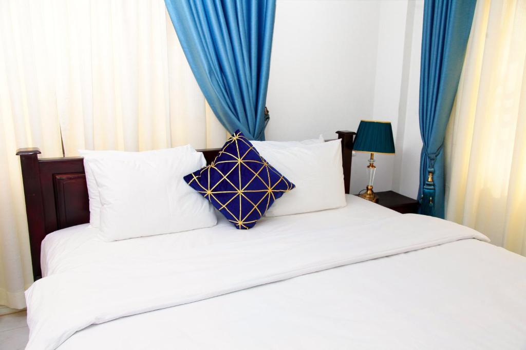 Schlafzimmer mit einem weißen Bett und blauen Vorhängen in der Unterkunft Vovole Luxury Homes in Kwedonu