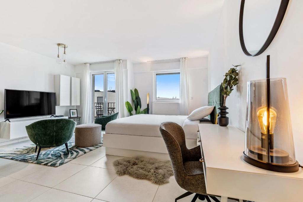 a white bedroom with a bed and a desk and chairs at Stylish Studio with King Bed, Balcony and Full Kitchen in Luxembourg