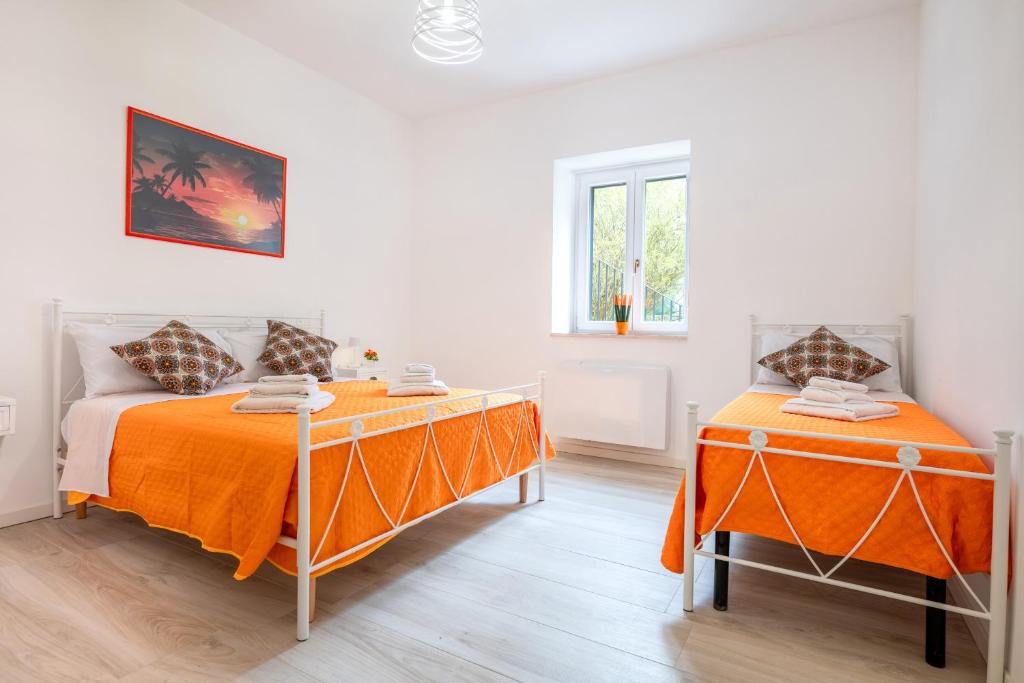 two beds in a white room with orange sheets at La Villa - Rainbow House in Martina Franca