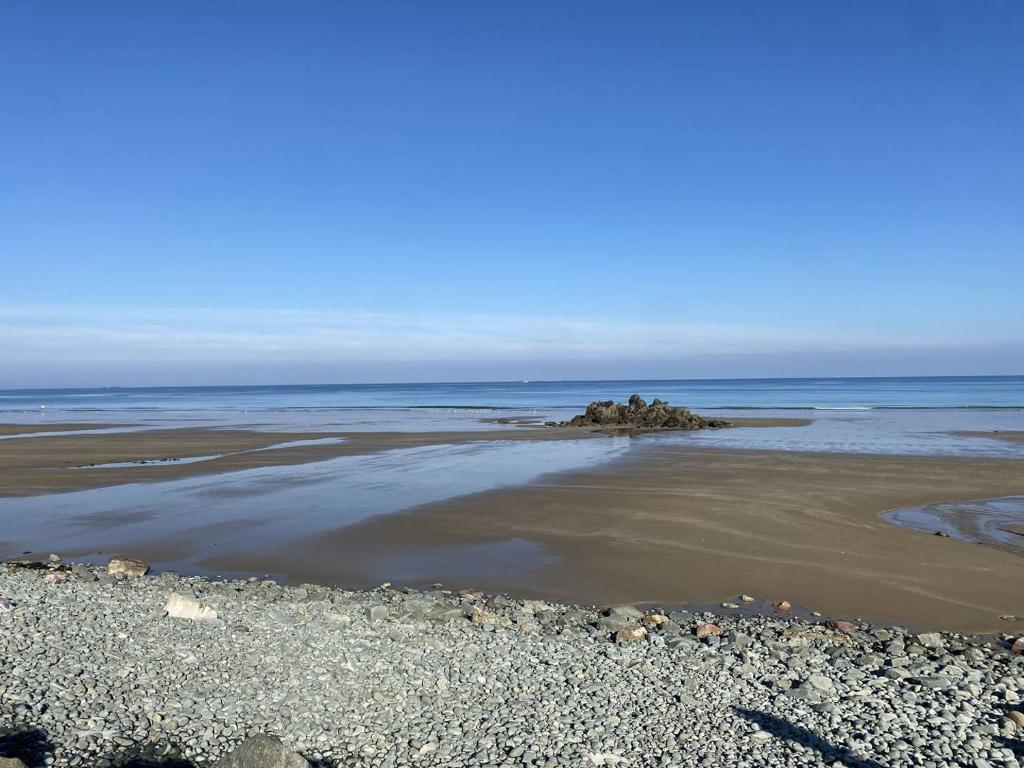 - une plage avec des rochers dans l'eau dans l'établissement 491 - Maison unique, les pieds dans l'eau, le long de la plage de Saint-Pabu, à Erquy