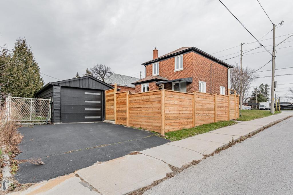 une maison avec une clôture en bois à côté d'une allée. dans l'établissement Victoria Park Suite, à Toronto