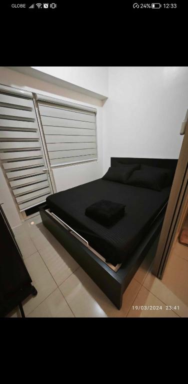 a black bed in a room with a window at Jans Staycation in Manila