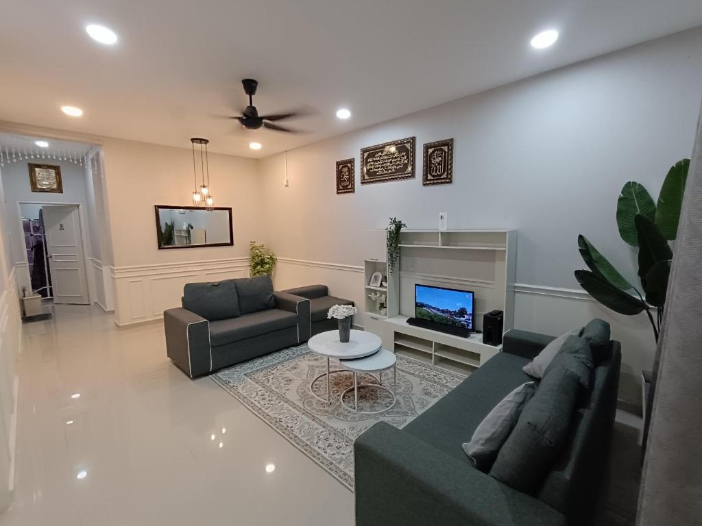 a living room with two couches and a tv at JRC Homestay Kerteh in Kemaman