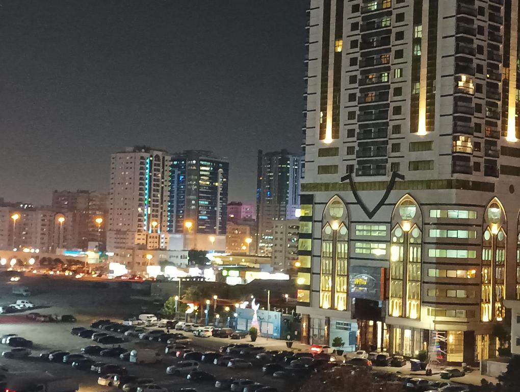 uma cidade à noite com carros estacionados num parque de estacionamento em Master Room With Attached Washroom For You em Ajman