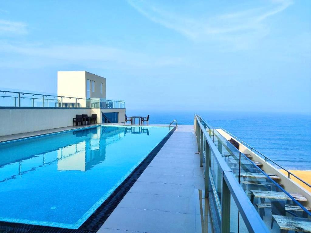 a swimming pool with the ocean in the background at Ocean Breeze Sea Haven Luxury Apartments in Negombo