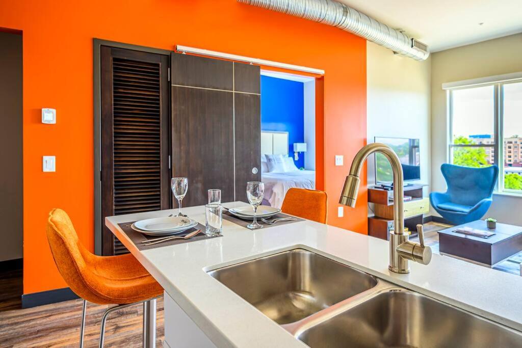 a kitchen with a sink and orange walls at Private Downtown Apartment With City View in Raleigh