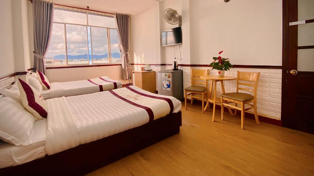 ein Hotelzimmer mit zwei Betten und einem Tisch und Stühlen in der Unterkunft Tường Vy Dalat Central in Da Lat