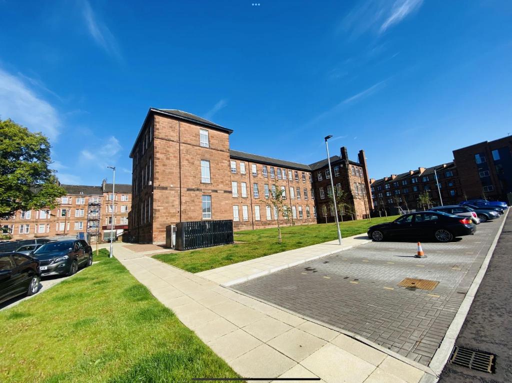 a parking lot with cars parked in front of a brick building at North Kelvin Guest House in Glasgow