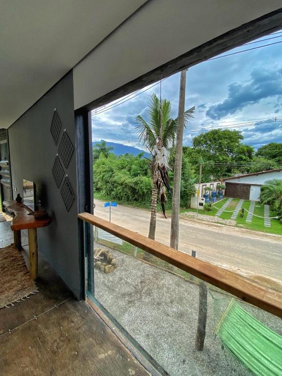 a room with a window looking out at a palm tree at C-house in Ubatuba