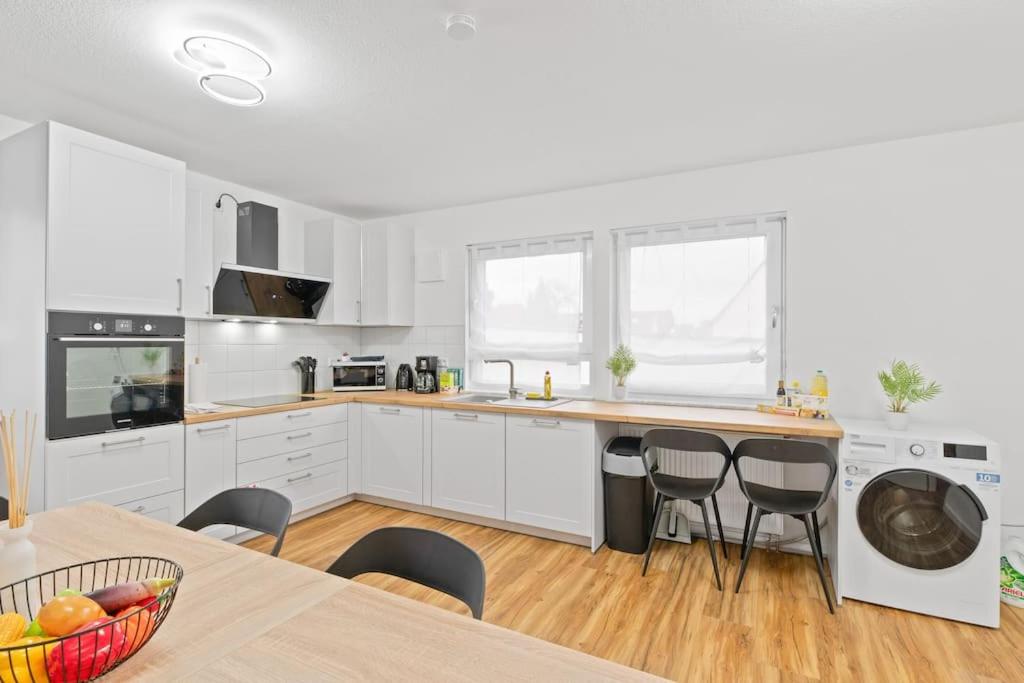 a kitchen with white cabinets and a table and chairs at W01 Große Wohnung für Teams in Wendlingen am Neckar