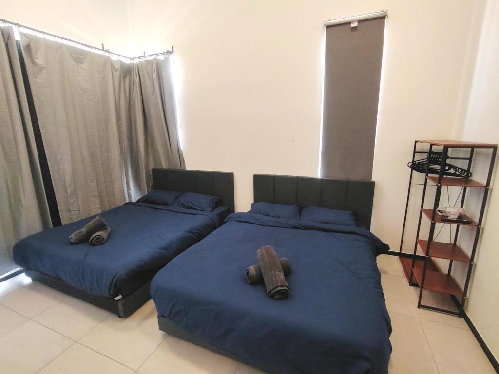 1 Schlafzimmer mit 2 Betten mit blauer Bettwäsche und einem Regal in der Unterkunft Sweet Stay in Jelutong