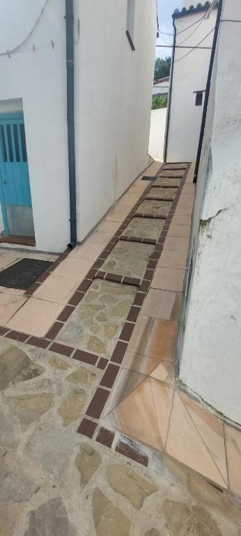 a walkway leading to a white building with a blue door at El callejón in Benarrabá