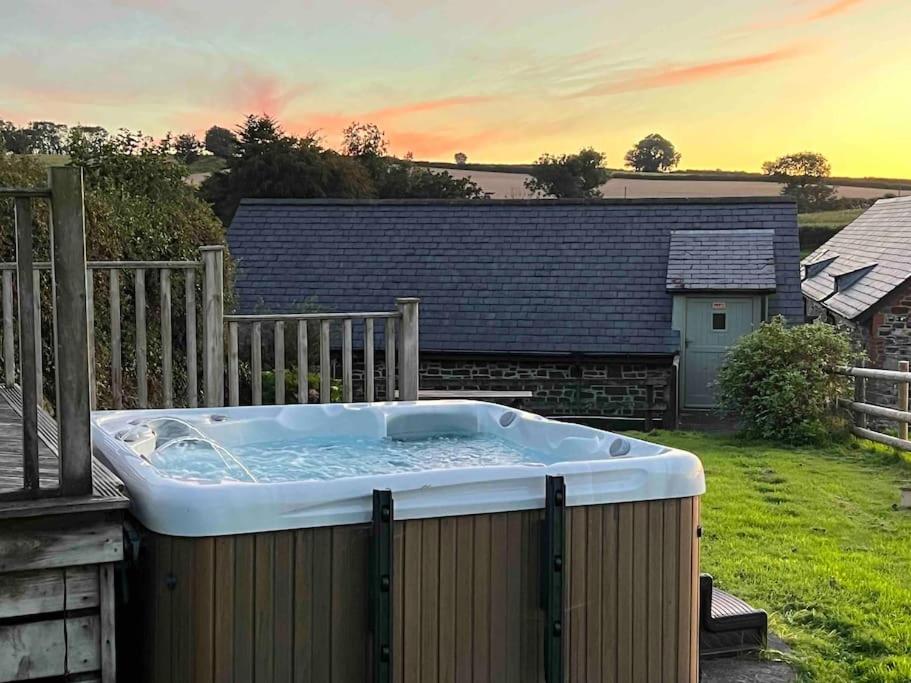 uma grande banheira de hidromassagem sentada ao lado de um quintal em Countryside cottage with private garden & hot tub em Lifton