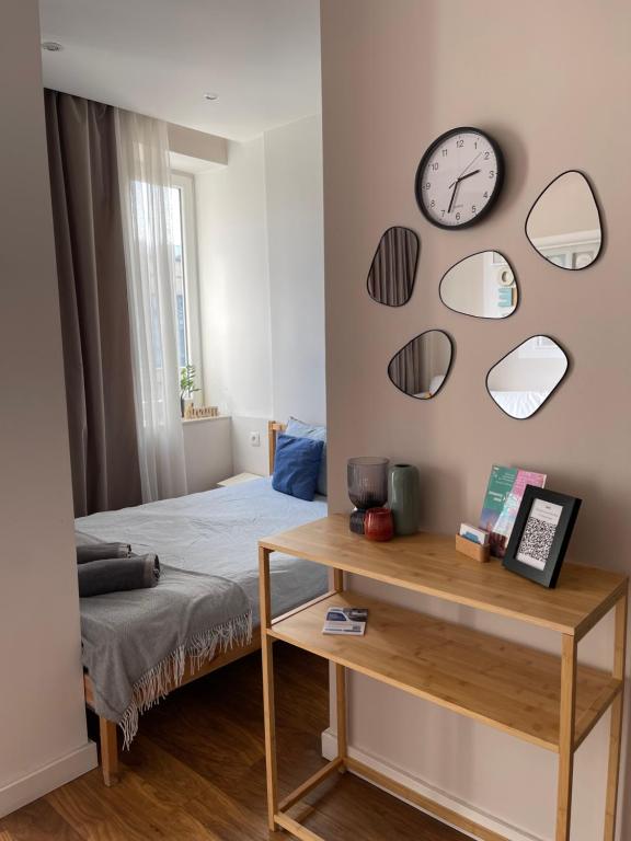 1 dormitorio con 1 cama y reloj en la pared en Studio w Centrum Warszawy ulica Chmielna - 500m od dworca Centralnego - by Good Sleeping, en Varsovia