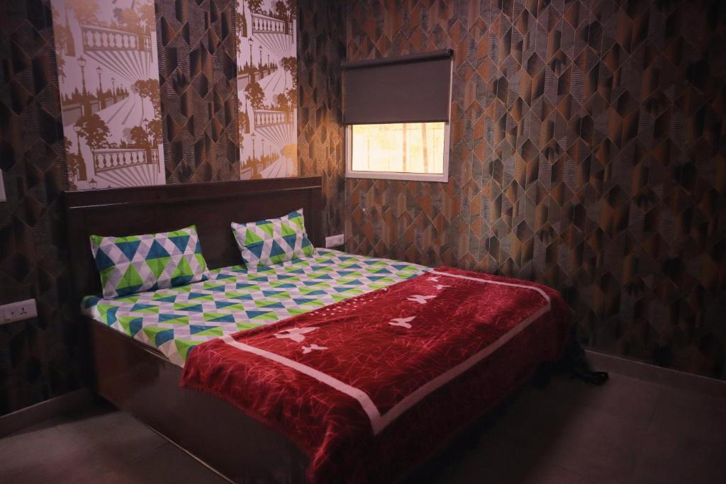 um pequeno quarto com uma cama com um edredão vermelho em NBR Resort em Noida