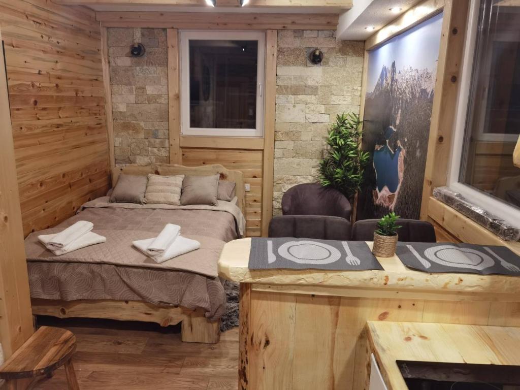 um pequeno quarto com uma cama e uma mesa em Nikolina apartments em Žabljak