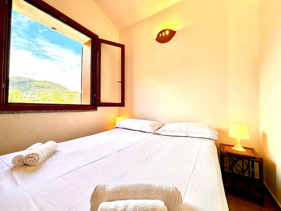 a bedroom with a large white bed with a window at Natural Home, Villasimius in Villasimius