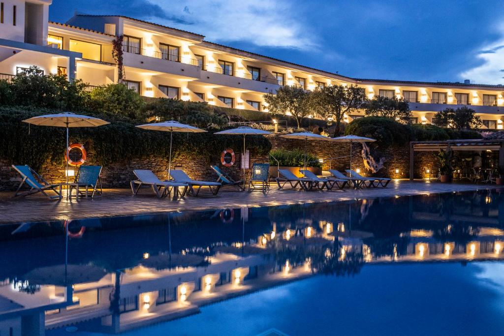 un hôtel avec une piscine dotée de tables et de parasols dans l'établissement Hotel Sol Ixent, à Cadaqués