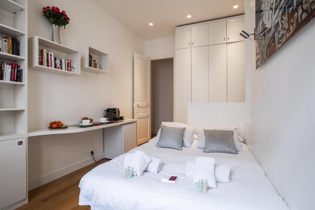 une chambre avec un lit blanc et un bureau dans l'établissement Tiny House St Germain, à Paris