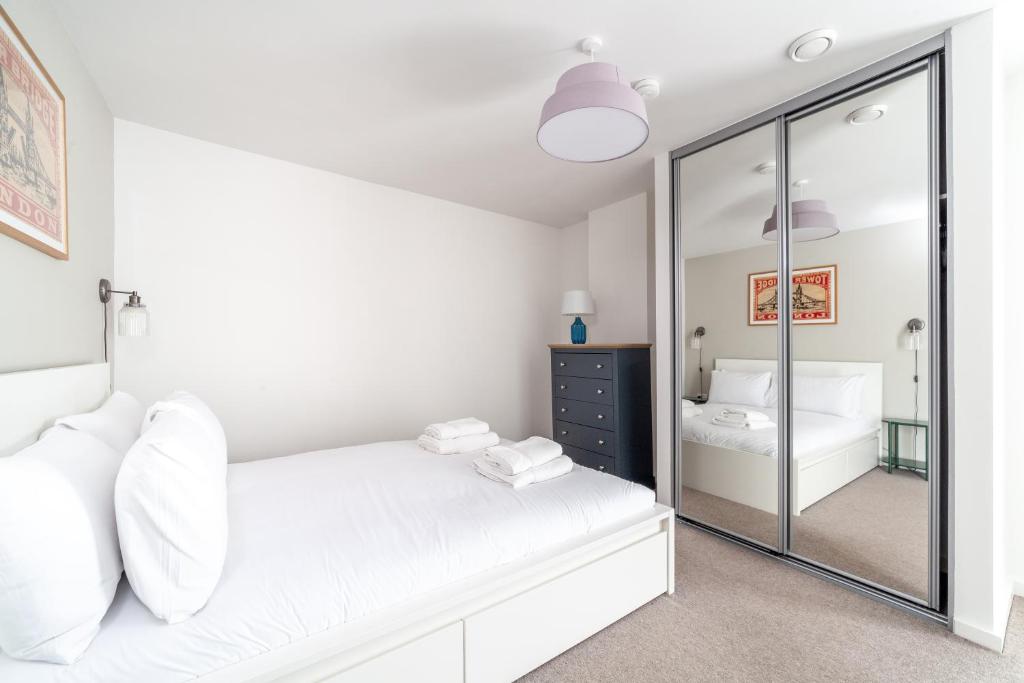 a bedroom with a white bed and a mirror at Cosy East London Retreat in London