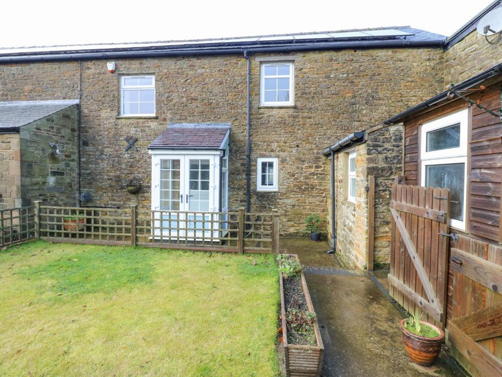 an old brick house with a fence and a yard at The Byre in Hexham